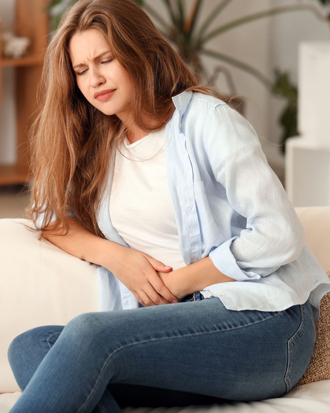 Mulher sentada com desconforto abdominal relacionado à saúde intestinal