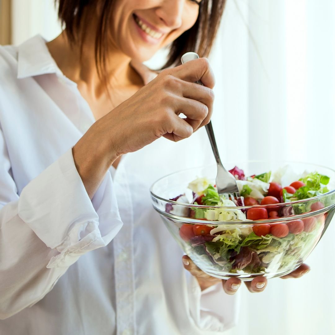 Mulher sorrindo segurando bowl com salada colorida