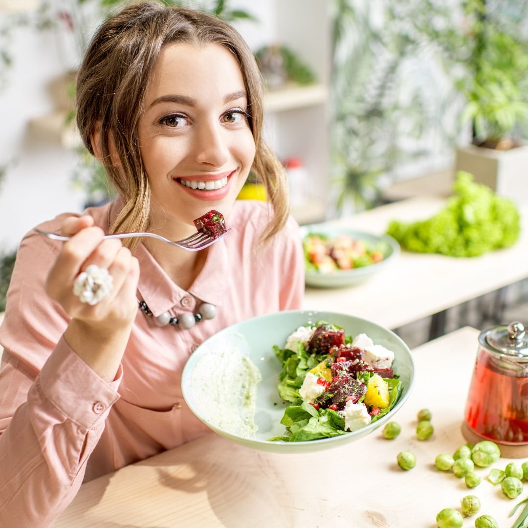 Mulher sorrindo enquanto consome refeição com salada